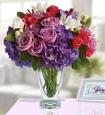 One sided arrangement of 8 Purple Roses ,8 Red Roses , 3 stems of White Chrysanthemum, 1 stem of White Lily and 2 Purple Hydrangea in a Glass Vase Affection